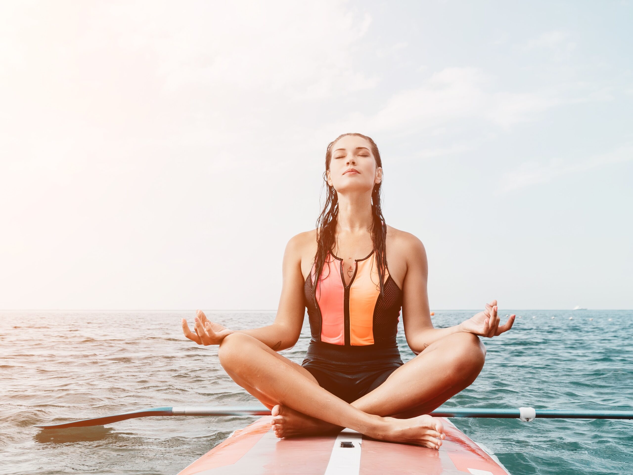 Mujer haciendo yoga sobre una tabla de paddle surf